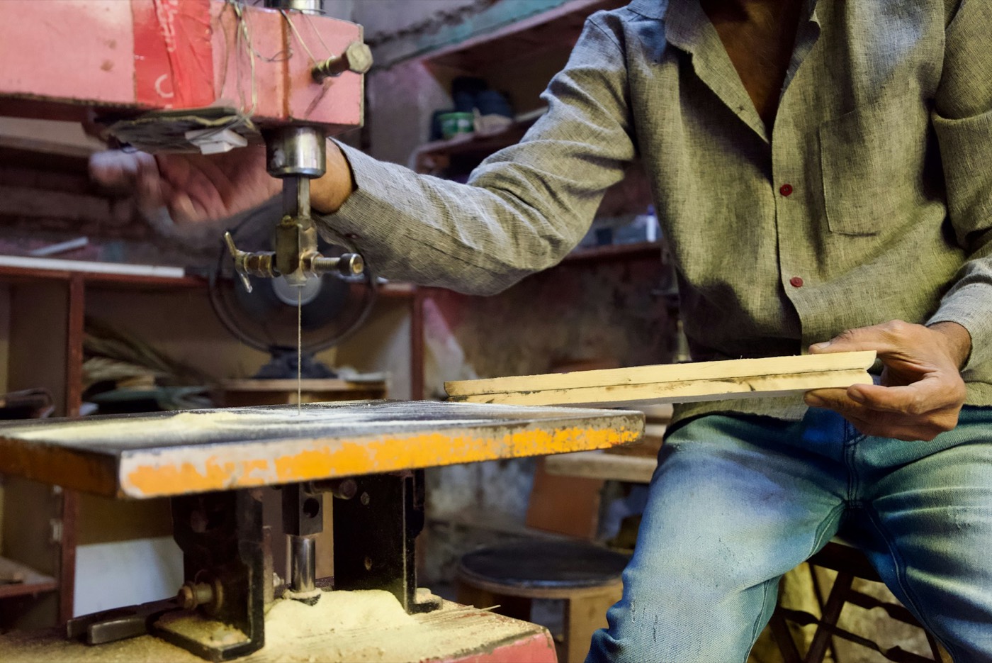 A craftsperson cutting wood in an active workshop